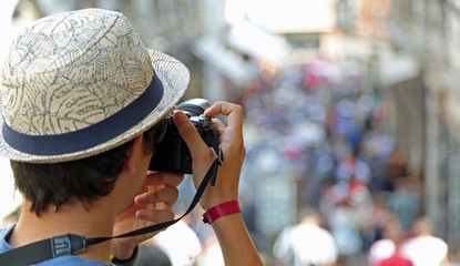 guy with a hat photographs people walking