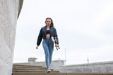 Fototapeta Miasto - Teenage girl walking with a skate board