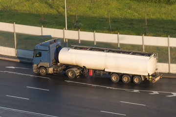 Wall Mural - Truck with a trailer white tank on the highway in the sunset light.