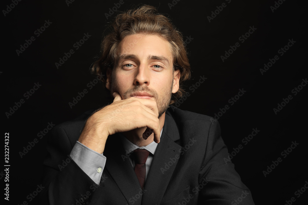 Portrait of young handsome businessman on black background
