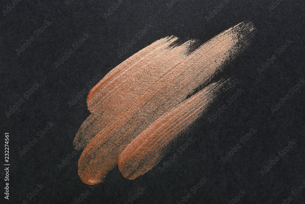 Strokes of gold paint on dark background