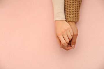 loving young couple holding hands on color background