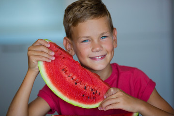 Cute kid enjoy summer juicy berry fruit watermelon Handsome blue eyes Boy wearing red t-shirt with slice of watermelon isolated on home studio kitchen.