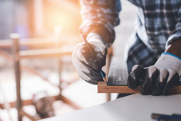 Confident wood worker expert. Young man working at factory. Skilled carpenter cutting a piece of wood in his woodwork workshop.