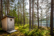 Autdoor Wooden Toilet In A Beautiful Sunny Forest Wilderness Landscape By A Lake.