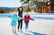 A group of three girls on a winter skating rink. Roll and laugh. Skating rink in nature.
