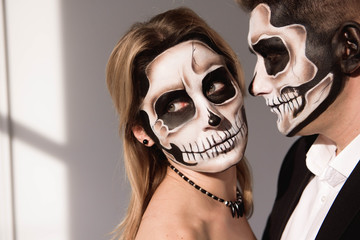 Couple with dark skull makeup on white background. Halloween