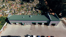 New Car Wash With Green Tiled Roof Stands In Front Of The Old Cemetery. Aerial View