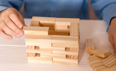 A man's hand lays down wooden blocks. Concept of business development, profit strategy, construction.