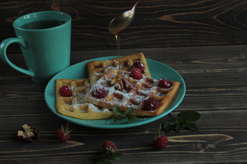 Waffles and raspberries are on a blue plate.