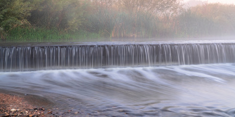 Wall Mural - Mornig fog over a river dam