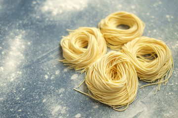 Wall Mural - Raw homemade spaghetti nest with flour on a grey background. Fresh Italian Cappellini pasta