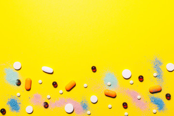 Wall Mural - Yellow medical background. Multicolored pills top view. childhood diseases. place for text. Copy space