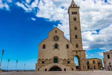 The beautiful Romanesque Cathedral Basilica of San Nicola Pellegrino, in Trani. Construction in limestone tuff stone, pink and white. A pointed arch under the bell tower. Italy, Puglia, Bari, Barletta