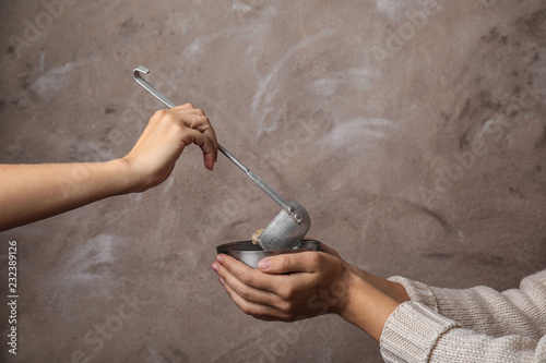 Fotomural Volunteer putting food into bowl of poor woman on color background, closeup