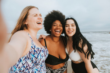 Wall Mural - Beautiful curvy women taking a selfie at the beach