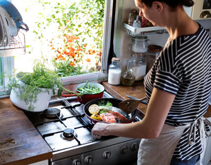 Woman cooking salmon in a pan