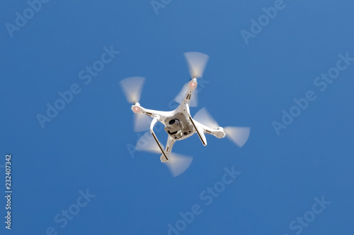 Cuadros en Lienzo Flying Dron with a camera on a blue sky background.