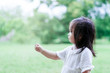 © livertoon - Asian cute little kid girl try to catch or touch something with her hand in the public park or garden.