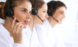 © rogerphoto - Call center operators at work. Focus at beautiful business woman in headset