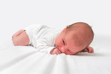 Newborn Baby Is Lying On Belly On White Blanket