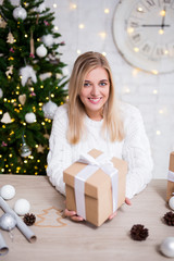 portrait of young beautiful blond woman with Christmas gifts in living room