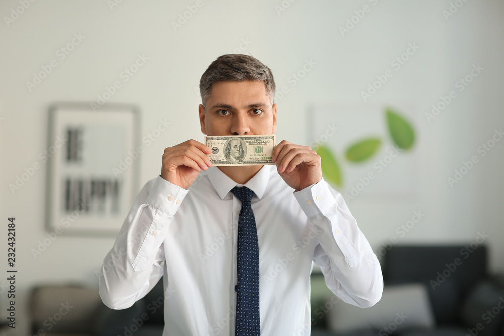 Businessman covering mouth with bribe. Corruption concept