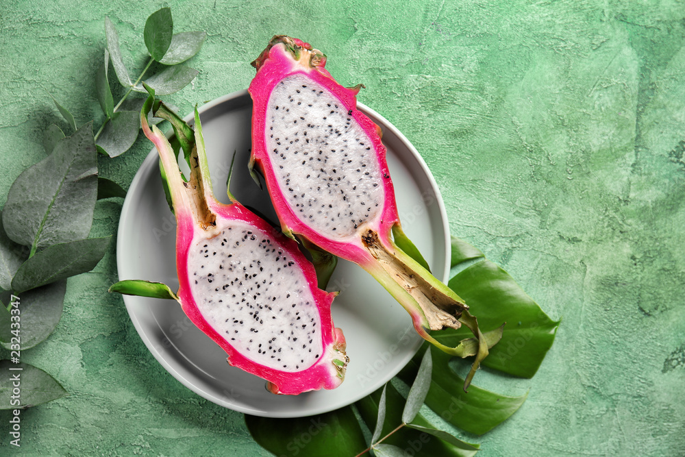 Plate with cut dragon fruit on color background