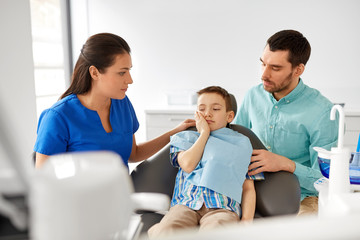 Sticker - medicine, dentistry and healthcare concept - father and son suffering from toothache visiting dentist at dental clinic