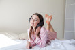 © dmitriisimakov - beautiful woman in pink Pajamas listening to music with headphones