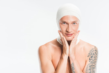 adult handsome man with bandages over head touching face after plastic surgery isolated on white