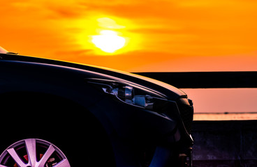 Blue compact SUV car with sport and luxury design parked on concrete road by the sea at sunset. Electric car technology and business. Hybrid auto and automotive industry. Tropical road trip travel.