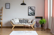 © Photographee.eu - Bright couch with pillows in real photo of white sitting room interior with posters, black lamp and pastel pink drapes