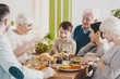 © Photographee.eu - Smiling boy sitting on grandfather's knees during family dinner with parents and grandmother