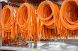 Coils of electrical wires for installation in cars, finished products on the racks in the factory. Industrial production, business organization. Orange wires for electric vehicles.