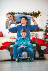 Wall Mural - Family with boy having fun playing at home in Christmas decorations