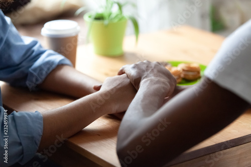 Cuadros en Lienzo Black african guy holds hand of beloved girl, sitting together at table expressing showing her sincere feelings or apologizing saying sorry