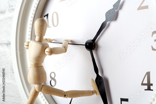 Fotografía Wooden human figure trying to stop the arrow of the clock