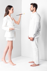 Wall Mural - adult female artist in total white holding palette and paintbrush in front of man