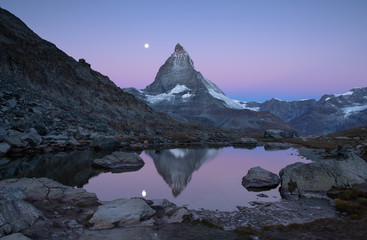 Fototapete - Twilight at the Riffelsee, with reflections of the Matterhorn and the full moon.