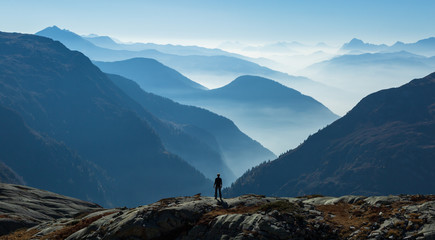 Man looking at the foggy, blue layers of mountains. Near Chamonix, France.