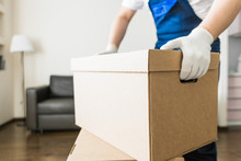 Delivery Man Loading Cardboard Boxes For Moving To An Apartment. Professional Worker Of Transportation, Male Loaders In Overalls
