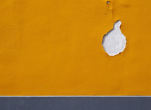 Bright Yellow Textured Paint On A Wall With Cracks And Hole Flaking Away And Grey Horizontal Stripe At The Bottom