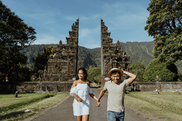 Wall Mural - couple running together through bali traditional gate