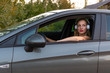 © ako-photography - A young, beautiful woman with long hair and headphones sits at the wheel of the car.