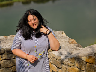 Wall Mural - Beautiful young girl with black hair posing against nature background.