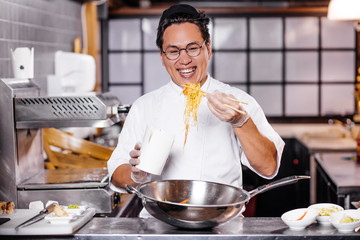 positive asian chef with noodle in the kitchen. close up photo.man preparing the order of customers. service concept