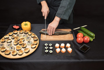 Wall Mural - man slicing fish on the cutting board. close up cropped photo.chef preparing raw tasty sushi. hobby, lifestyle