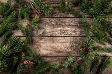 Wall Mural - Holiday background of Christmas fir branches, spruce, juniper, fir, larch, pine cones with light. Xmas and New Year theme. Top view, flat lay
