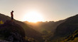 © Stocksy - Hiker standing on a rock and looking the sunset over mountains